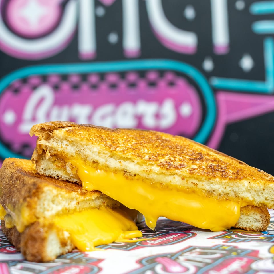 Grilled cheese sandwiches with golden toasted bread and melted cheese on a colorful diner-themed table.